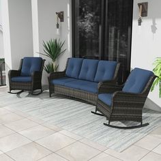 two wicker rocking chairs and a blue cushioned sofa on a patio with potted plants