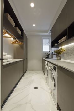 a washer and dryer in a small room with white marble flooring on the walls