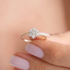 a woman's hand holding a gold ring with two flowers on the middle and one flower in the middle