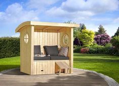 a wooden bench sitting on top of a lush green field next to a small gazebo