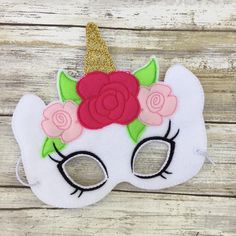 a white mask with pink flowers and a gold glitter horn on the top of it