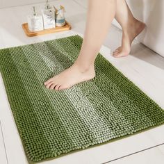 a person standing on a green rug in the bathroom