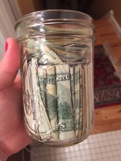 a person holding a jar full of money