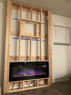 a wall mounted fireplace in a living room with wood framing around it and electric fire