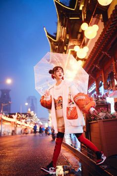 a woman holding an umbrella while standing in the rain on a city street at night