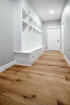 an empty room with white cabinets and wooden floors