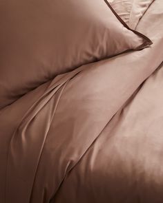 an unmade bed with brown sheets and pillowcases on top of each other