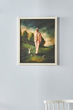 a painting hanging on the wall next to a chair and table with a white chair