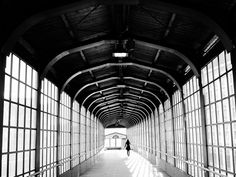 a person walking down a long hallway with lots of windows