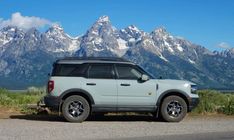 a white suv parked on the side of a road in front of mountains