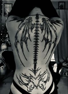 the back of a woman's body with tattoos on her ribs and wings in black and white