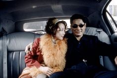 a man and woman sitting in the back seat of a car