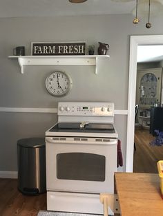 a white stove top oven sitting inside of a kitchen next to a wall mounted clock