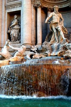 the fountain has statues on it and is surrounded by water