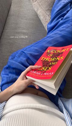 a person laying on a couch holding a book in their hand, with the cover pulled back