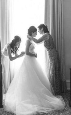 two brides helping each other get ready for their wedding