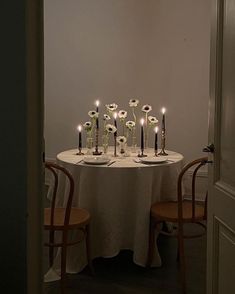 a table with candles and flowers on it in front of a doorway that leads to another room