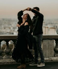 two people standing next to each other in front of a cityscape with the eiffel tower in the background