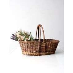 a wicker basket with flowers in it sitting on a table next to a white wall