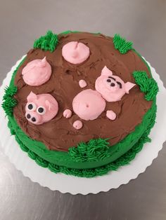 a cake decorated with green icing and pink frosting pigs on top of it