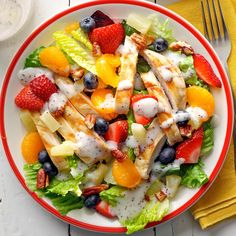 a salad with chicken, fruit and dressing on it