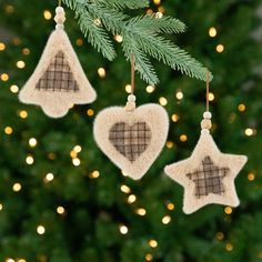 three ornaments hanging from a christmas tree with lights in the background