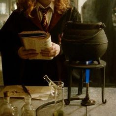 a woman in a harry potter costume reading a book next to an old caulder