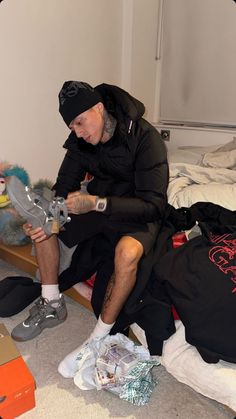 a man sitting on top of a bed holding a skateboard