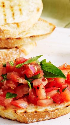 a piece of bread with tomato and basil on it next to some pita bread