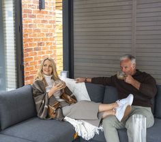 a man and woman sitting on a couch drinking coffee