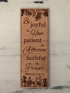 a wooden bookmark with the words be joyful in hope and an image of flowers