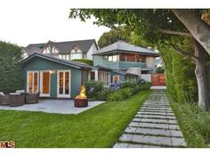 a house with a fire pit in the front yard next to it and landscaping on both sides