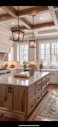 a large kitchen with an island in the middle and two hanging lights over it's sink