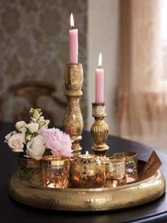 two candles are sitting on top of a tray with flowers and other items around it