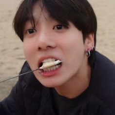 a young man is brushing his teeth on the beach