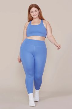 a woman in blue sports bra top and leggings, with her hands on her hips