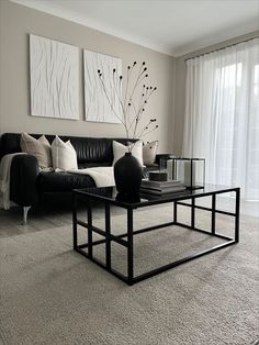 a black and white living room with couches, coffee table and paintings on the wall