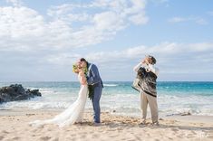 a bride and groom kissing on the beach