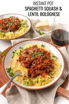 two plates of spaghetti with meat and vegetables on them, next to a glass of wine