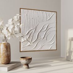 a vase with white flowers in it sitting on a shelf next to a wall hanging