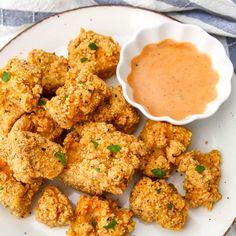 a white plate topped with tater tots next to a bowl of dipping sauce