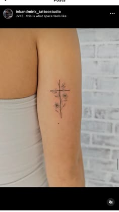 a woman's arm with a small cross tattoo on the back of her shoulder