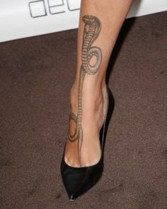 a woman's foot with a snake tattoo on her left leg and black high heels