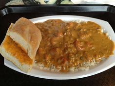 a white plate topped with rice and beans covered in gravy next to a sandwich