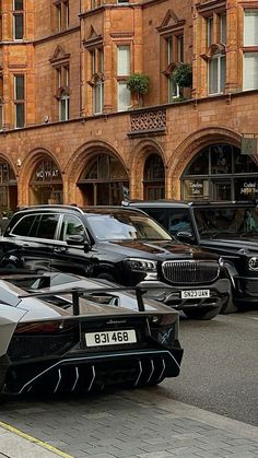 a row of cars parked on the side of a road next to a tall building