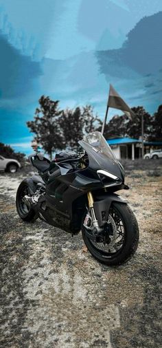 a black motorcycle parked on top of a dirt field