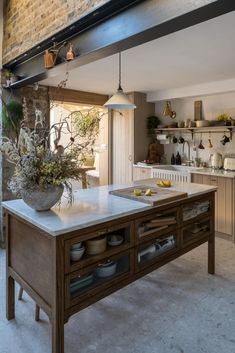 a kitchen with an island in the middle and shelves on the wall behind it,