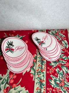 red and white plates with holly designs on them sitting on top of a table cloth