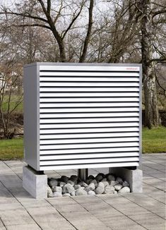 a large white box sitting on top of a brick floor next to a park filled with trees