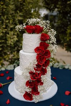 a wedding cake with red roses and baby's breath